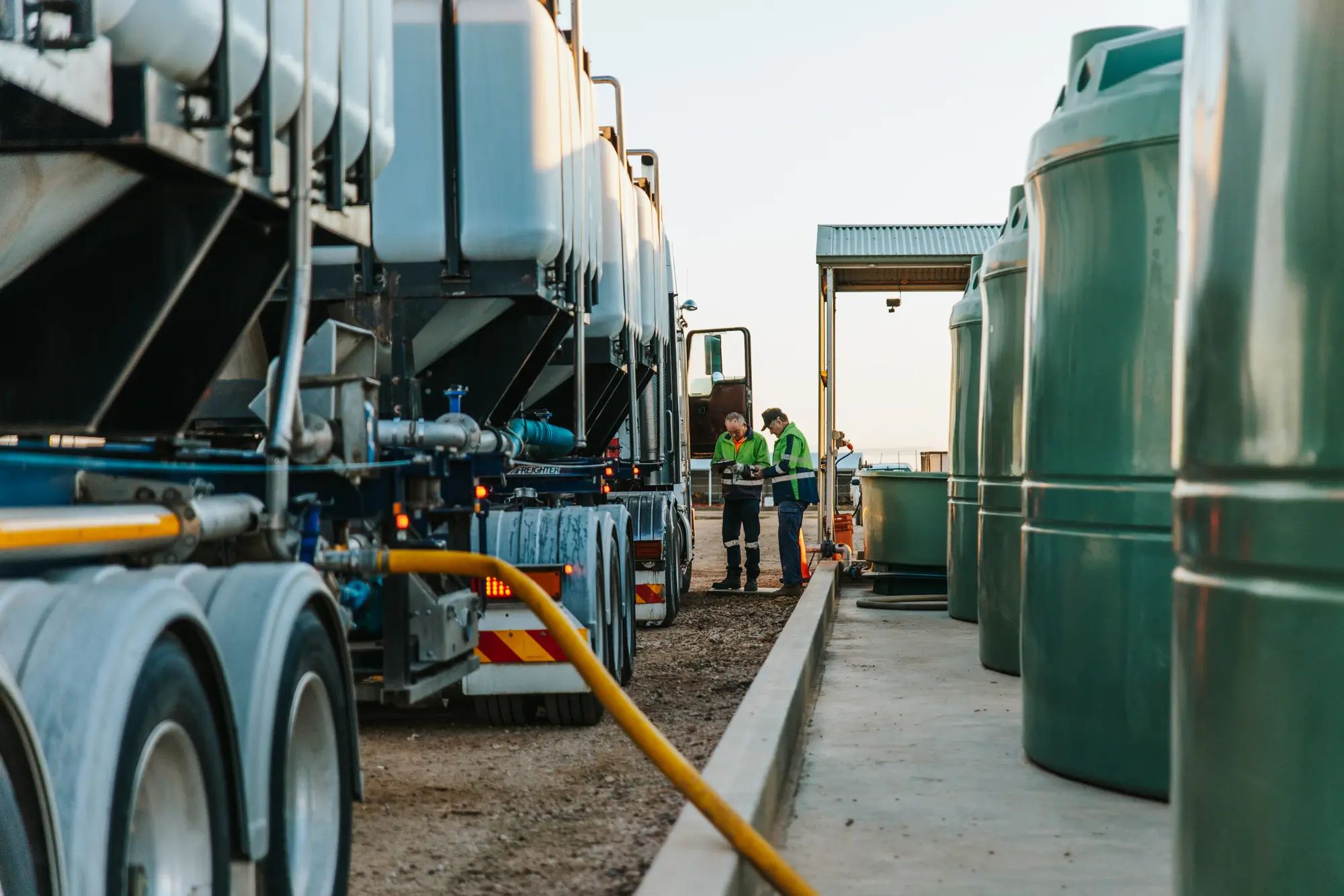 Fertiliser tanks on an Australian farm with workers inspecting, highlighting liquid fertiliser and agronomy by NuEdge.