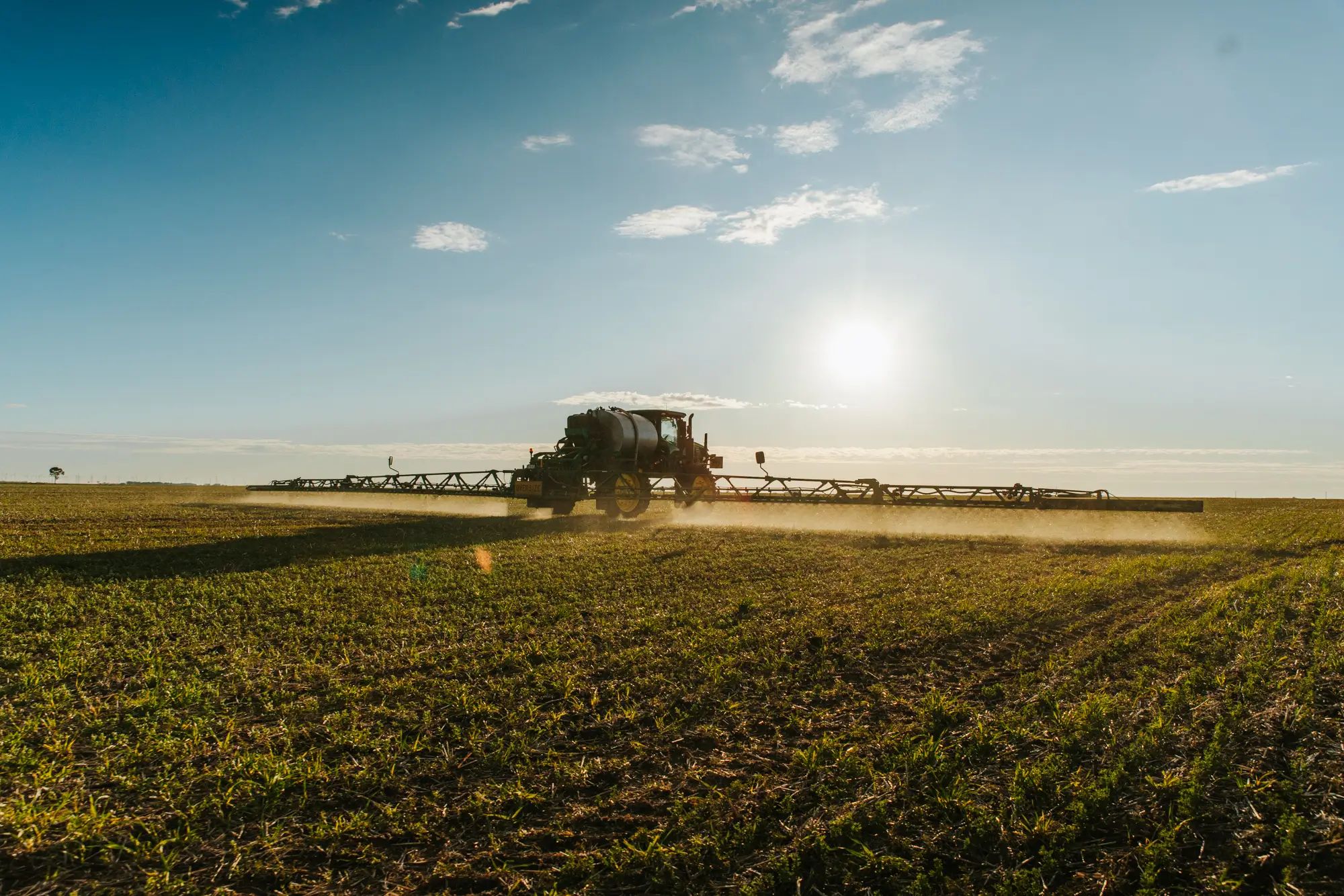 Tractor spraying liquid fertiliser on a field at sunset, enhancing soil nutrition and promoting healthy crops on an Australian farm.