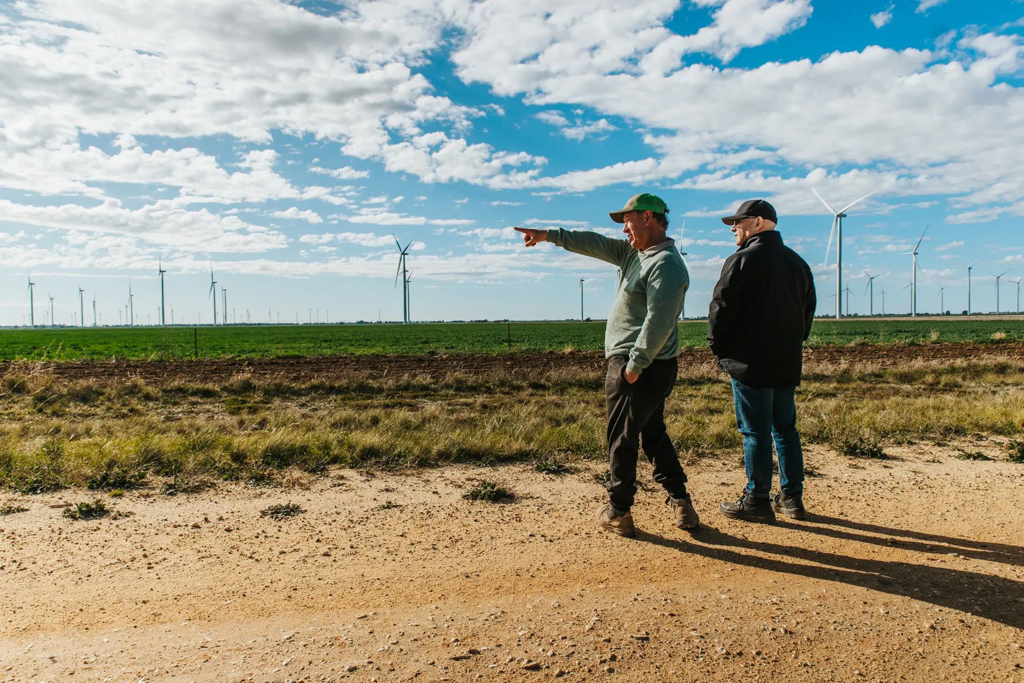 Farmers discussing the landscape at a wind farm, highlighting the potential for liquid fertiliser use on an Australian farm.